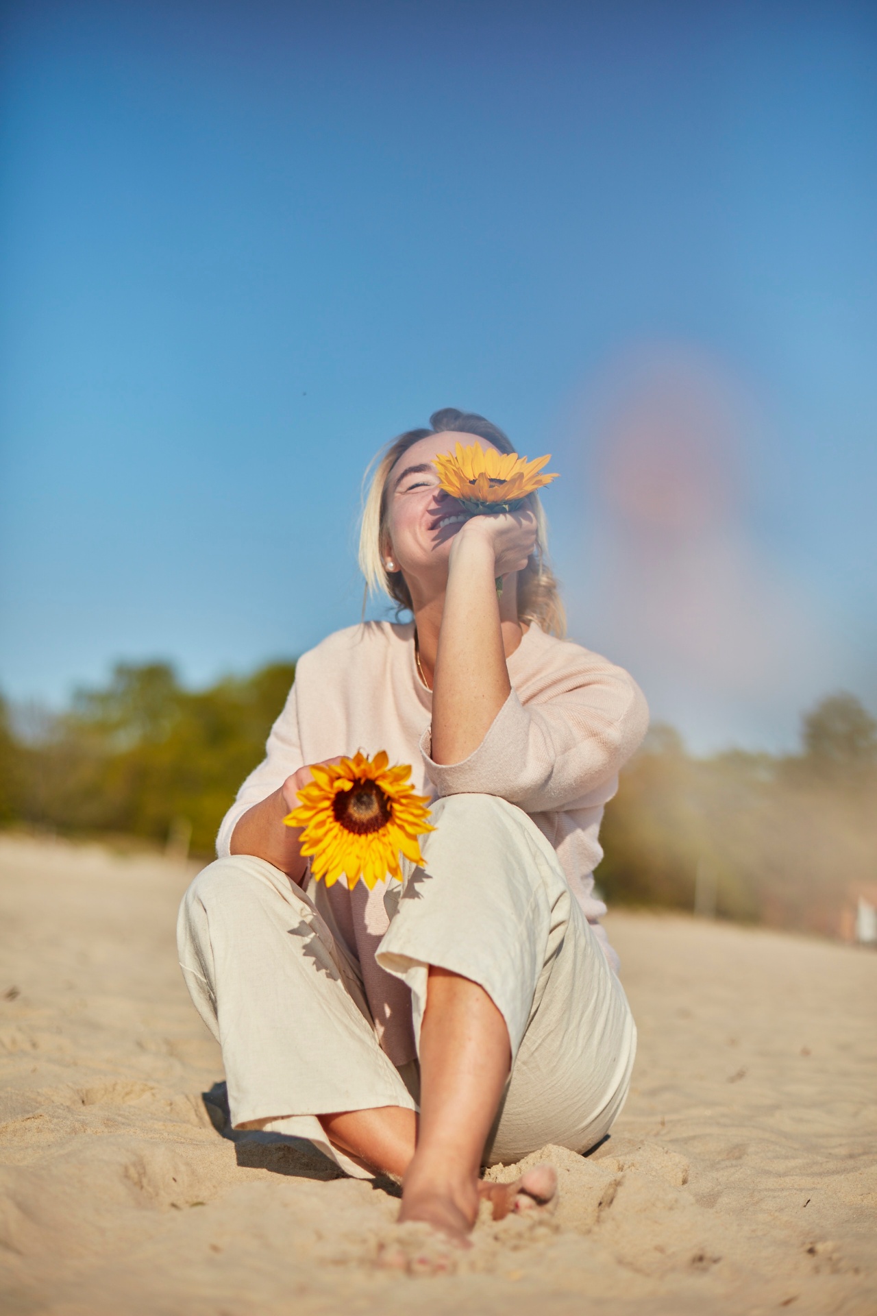 Joanna sitting on the beach with a sunflower